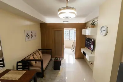 a living room with a couch and a clock on the wall at shell residences condo walk to Mall of Asia in Manila