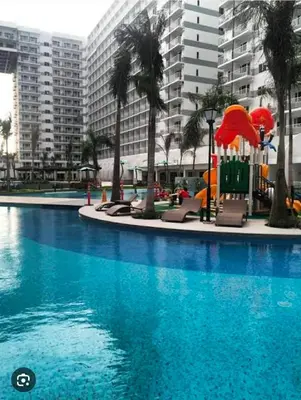a swimming pool with chairs and umbrellas in a building at shell residences condo walk to Mall of Asia in Manila