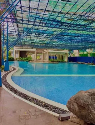 a large swimming pool with blue water in a building at Mandarin Suite Stay in Manila