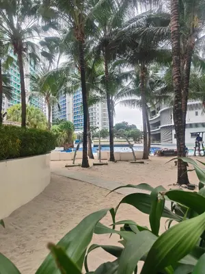 a sandy beach with palm trees and buildings at Azure Urban Resort residence's Staycation by angkol limo in Manila