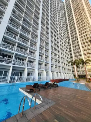 a large building with a swimming pool and two tall buildings at Modern 1BRH Condotel Stunning City ViewSea Views in Manila