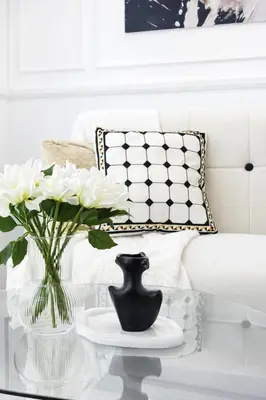a glass coffee table with a vase and white flowers at Calme Corner Azure Urban Residences Maldives Tower in Manila