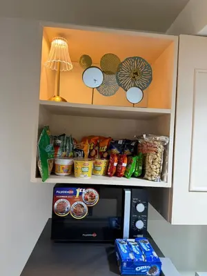 a kitchen with a microwave with food on top of it at Luxe staycation by Joy at Charm Residence Cainta in Manila