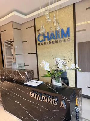 a lobby with a building a sign and flowers at Luxe staycation by Joy at Charm Residence Cainta in Manila