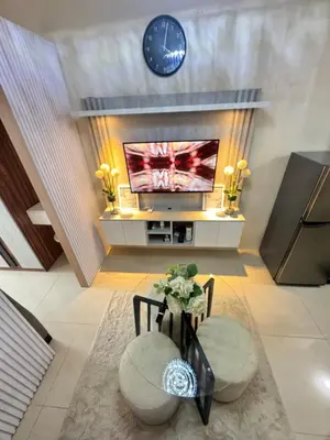 a living room with a tv and a table and a clock at Affordable Airport Staycation SMDC Field Residence in Manila