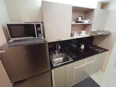 a small kitchen with a sink and a microwave at Casa Rosie in Seibu Tower - homey 1BR near BGC High Street in Manila