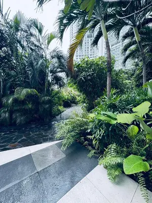 a tropical garden with palm trees and a walkway at Pahinga Luxury Stays in Manila