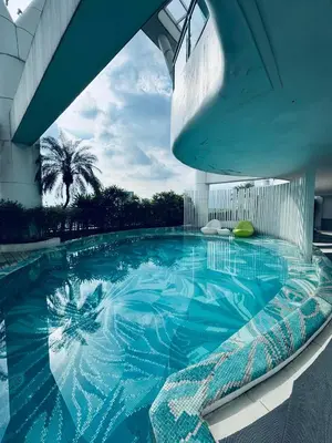 a large swimming pool in a building with a palm tree at Pahinga Luxury Stays in Manila