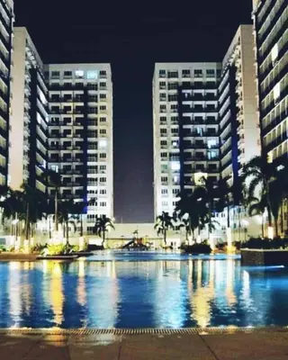 a large swimming pool with two tall buildings at night at NEAR SMX, MOA Sea Residence Condotel in Manila