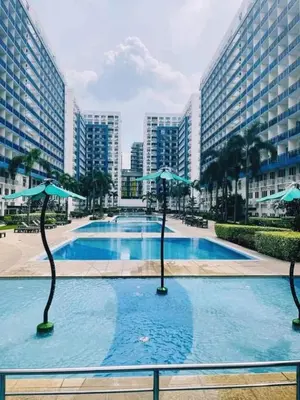 a large swimming pool with umbrellas in a city at NEAR SMX, MOA Sea Residence Condotel in Manila