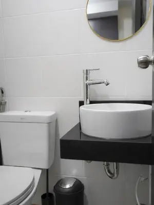 a bathroom with a sink and a toilet and a mirror at Maison Inea in Manila