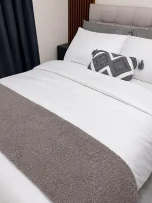 a white bed with a black and white pillow on it at Maison Inea in Manila
