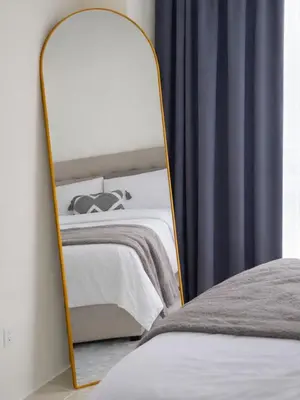 a mirror next to a bed in a room at Maison Inea in Manila