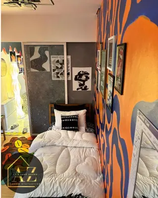 a bedroom with two beds and a wall with paintings at Azure Staycation by Adie Luxe Haven in Manila