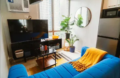 a blue couch in a living room with a tv at Spacious 1-BR Condo near BGC w Pool and Gym in Manila