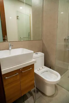 a bathroom with a sink and a toilet and a mirror at Spacious 1-BR Condo near BGC w Pool and Gym in Manila