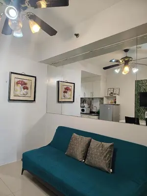 a living room with a blue couch and a kitchen at Sea Residences Feliz in Manila