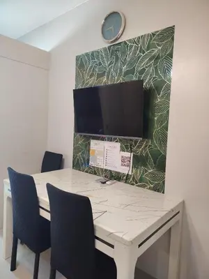a table with chairs and a clock on a wall at Sea Residences Feliz in Manila