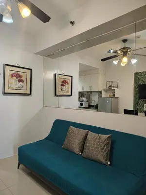 a blue couch in a living room with a kitchen at Sea Residences Feliz in Manila