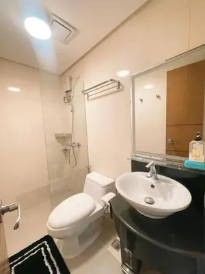 a bathroom with a toilet and a sink and a mirror at Venice McKinley Stay with Pool, Gym, fast Wifi and Netflix in Manila
