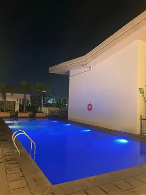 a blue swimming pool at night on a building at Venice McKinley Stay with Pool, Gym, fast Wifi and Netflix in Manila