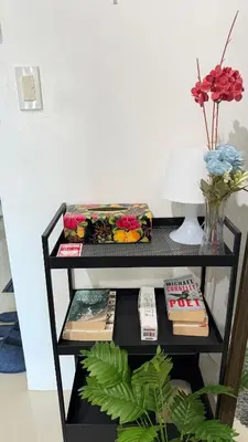a black shelf with books and a vase with flowers at Jazz staycation makati by as in Manila