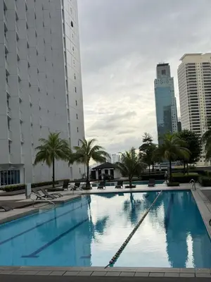 a large swimming pool with palm trees and buildings at Jazz staycation makati by as in Manila