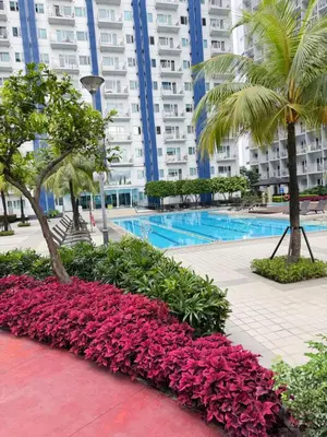 a swimming pool with flowers in front of a building at Jazz staycation makati by as in Manila