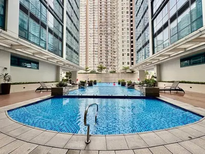 a large swimming pool in a building with tall buildings at Uptown Home 1BR at One Uptown Residence BGC in Manila
