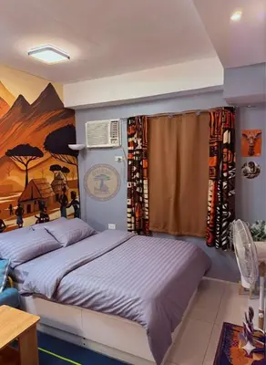 a bedroom with two beds and a painting on the wall at Cozy African Themed Unit in Parañaque in Manila