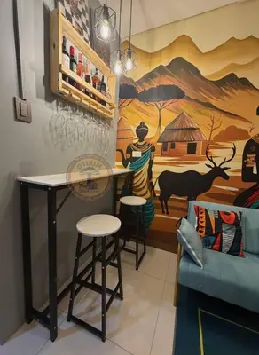 a room with a table and chairs and a mural at Cozy African Themed Unit in Parañaque in Manila