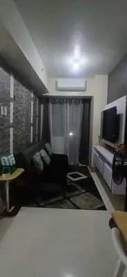 a living room with a black couch and a flat screen tv at R&A staycation in Manila