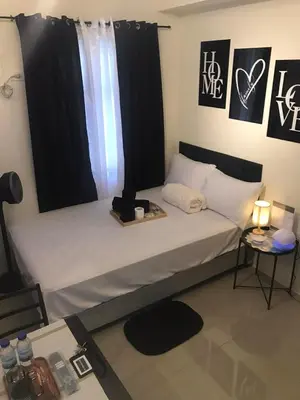 a bedroom with a bed with white sheets and a window at InMer's D Staycation in Manila