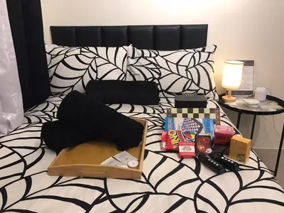 a bed with a black and white comforter with food and drinks at InMer's D Staycation in Manila
