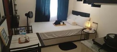 a small bedroom with a bed and a table with a lamp at InMer's D Staycation in Manila