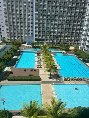 an overhead view of a pool with palm trees and a large building at Jazz Staycation Makati By As in Manila