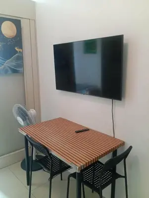 a wooden table with chairs and a television on a wall at Suite hotel at Mall of Asia - Tes Ualat in Manila