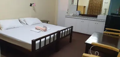 a bedroom with a bed and a table and a kitchen at Cool Martin Family Hotel and Resort in Bacoor