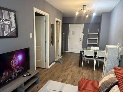 a living room with a television and a dining room at The Gramercy Residences in Manila