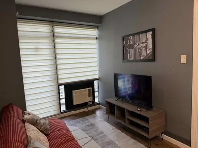 a living room with a flat screen tv and a fireplace at The Gramercy Residences in Manila