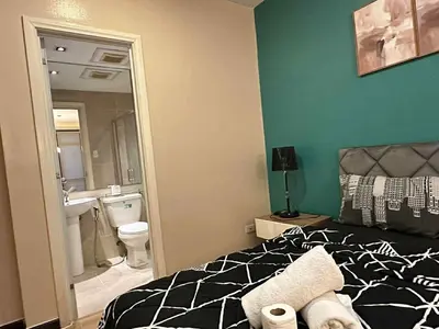 a bedroom with a black and white bed and a bathroom at The Gramercy Residences in Manila