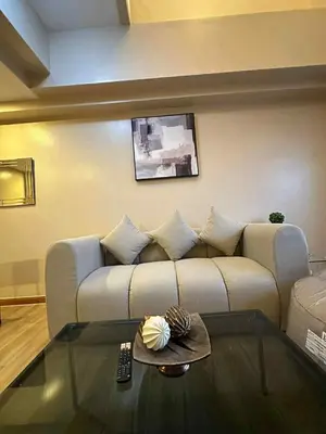 a living room with a couch and a glass table at The Gramercy Residences in Manila
