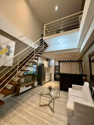 a living room with a staircase with a couch and a table at The Gramercy Residences in Manila