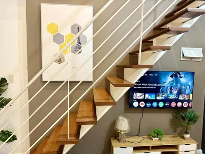 a living room with stairs with a tv at The Gramercy Residences in Manila
