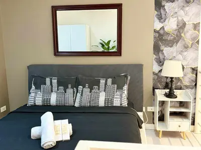 a bedroom with a bed with a picture of buildings at The Gramercy Residences in Manila