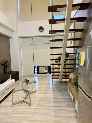 a living room with a couch and a glass table at The Gramercy Residences in Manila