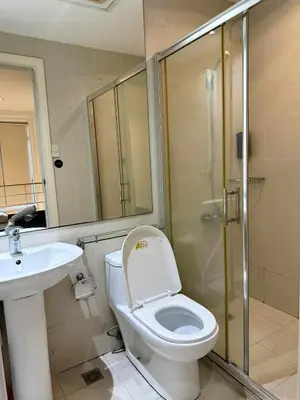 a bathroom with a toilet and a sink and a shower at The Gramercy Residences in Manila