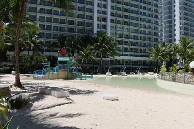 a beach with a playground in front of a building at Azure Residences Staycation in Manila