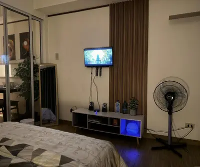a bedroom with a tv and a fan and a bed at Azure Residences Staycation in Manila