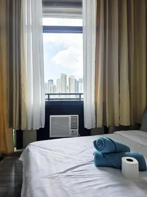 a bedroom with a bed with a view of a city at Stay in Makati 1-BR Condo with Pool, Fast WiFi, Gym, Balcony in Manila